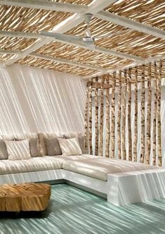 a living room filled with lots of white furniture and bamboo screens on the wall behind it