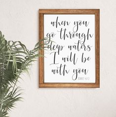 a wooden frame hanging on the wall above a potted plant and a framed quote