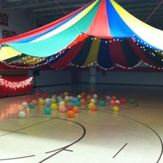 an indoor basketball court decorated with balloons and lights for a circus themed birthday or baby shower