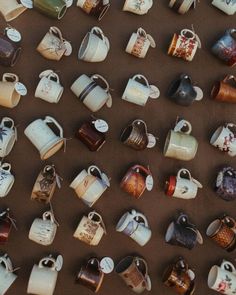 there are many different cups and mugs on the table together with tags attached to them