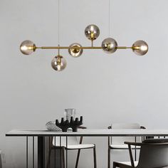 a dining room table with four lights hanging from it's ceiling and chairs around it