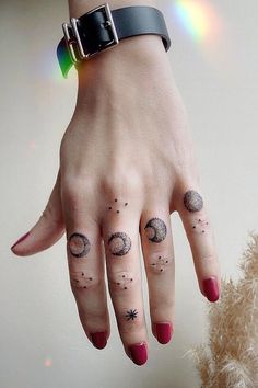 a woman's hand with tattoos on her fingers and the moon phases tattooed on it