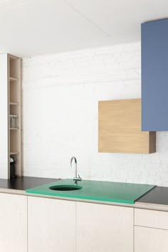 a kitchen with white brick walls and green counter tops, along with an aqua sink