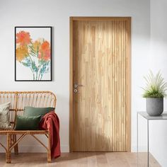 a wooden door in a white room next to a bench and potted plant on the wall