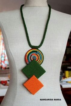 a white mannequin with a green and orange necklace on it