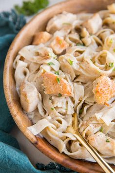 a wooden bowl filled with pasta and chicken