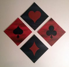 four cards with hearts and spades on them are hanging on the wall above a toilet