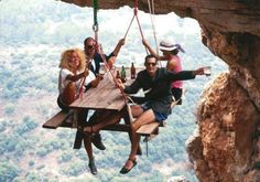 four people sitting on a wooden table in the middle of a cliff with text that reads, good morning from sheila teng