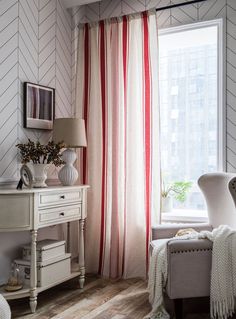 a living room with white furniture and red striped drapes on the window sill