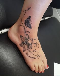 a woman's foot with a butterfly and flower tattoo on the bottom of it