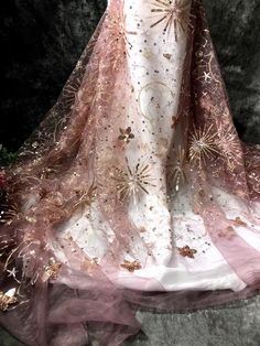 a pink and white dress with gold sequins on the skirt is displayed in front of a black background