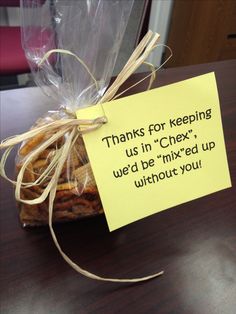 a note attached to a piece of bread on top of a wooden table next to a plastic bag filled with cookies