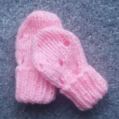 two pink knitted mittens laying on top of a gray carpet next to each other