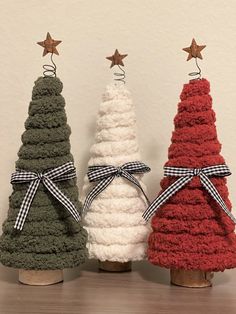 three knitted christmas trees in different colors and sizes, tied with bows on top