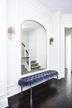 a blue bench sitting in front of a mirror on a wall next to a stair case