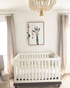 a baby's room with a white crib, chair and chandelier