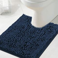 a blue bath mat sitting on top of a bathroom floor next to a white toilet