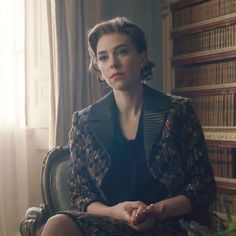 a woman sitting in a chair next to a bookshelf