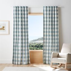 a rocking chair in front of a window with blue and white checkered drapes