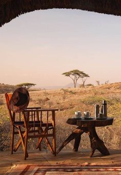 a table with two chairs and a hat on it in the middle of an open field