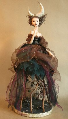 a doll sitting on top of a table wearing a dress and headpiece with horns