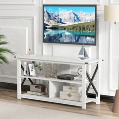 a flat screen tv mounted to the side of a wall next to a table and lamp