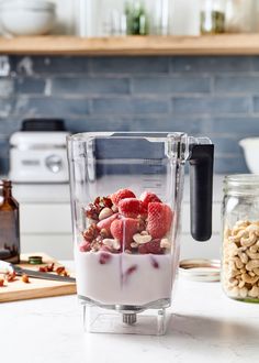 a blender filled with yogurt, nuts and raspberries on top of a counter