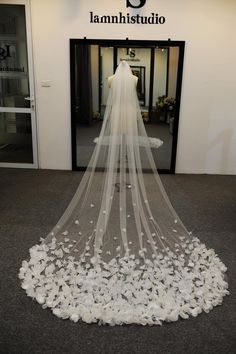 a white wedding veil with flowers on the floor in front of a storefront window