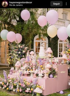 a table covered in lots of balloons next to flowers and cake on top of it