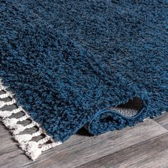 a blue rug on the floor with a wooden floor in front of it and an area rug that has been rolled over