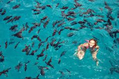 a woman swimming in the ocean surrounded by fish