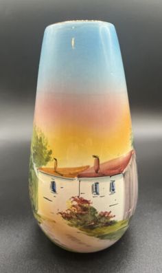 a small vase with a house painted on it