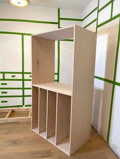 an empty room with green lines painted on the walls and wooden shelves in front of it