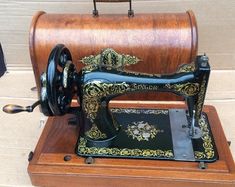 an antique sewing machine sitting on top of a wooden stand