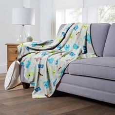 a couch with a blanket on top of it in front of a lamp and window