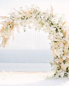 a white wedding arch decorated with flowers and feathers