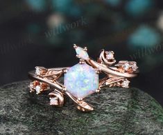 an opal and diamond ring sitting on top of a rock