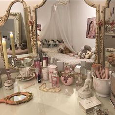 a vanity with a mirror, candles and other items on it in front of a bed