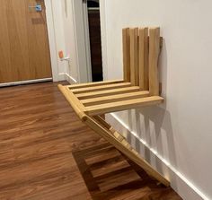 a wooden chair sitting on top of a hard wood floor next to a white wall