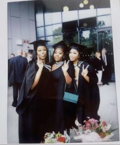 three women in graduation gowns posing for a photo with one woman giving the peace sign