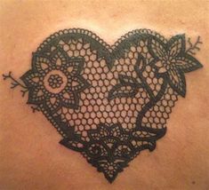 a black lace heart tattoo on the back of a woman's shoulder