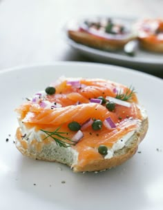 a bagel with salmon and capers on it is sitting on a white plate