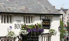 a white building with flowers in the window boxes on it's front and side