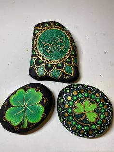 three painted rocks with shamrocks on them