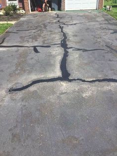 a man sitting in the doorway of a house next to a driveway that has been cracked