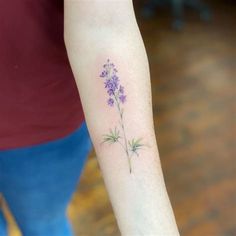 a small purple flower tattoo on the arm