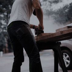 a man sanding wood with an electric grinder on the back of his car