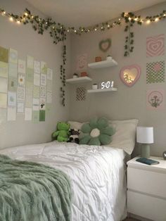 a bedroom decorated in pastel green and white with string lights strung from the ceiling