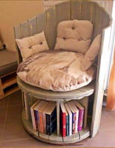 a bed made out of an old chair with pillows on it and books in the corner