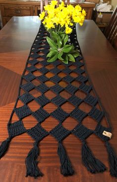 a crocheted table runner with yellow flowers in it on top of a wooden table